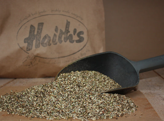 Haith's crushed hemp seed for fishing inside a scoop in front of Haith's paper bag