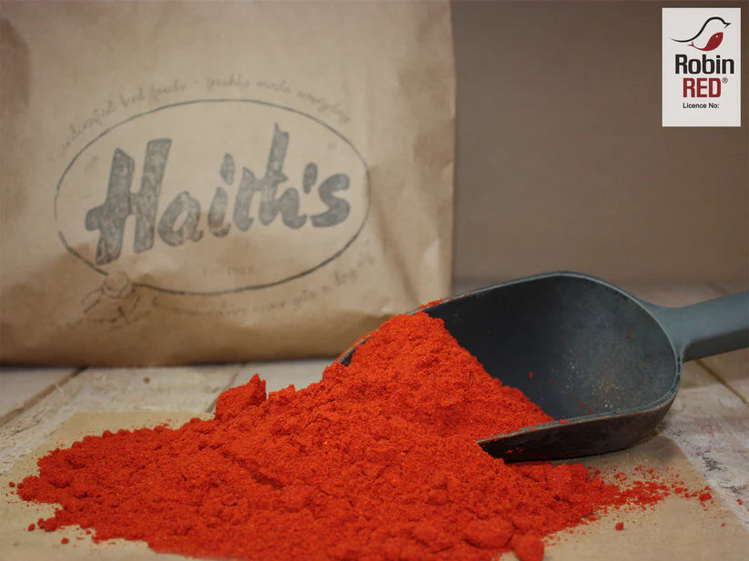 Red powder with a scoop and 'Haith's' branded bag on a wooden surface.